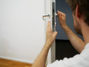Locksmith replacing mortice lock on white wooden door 