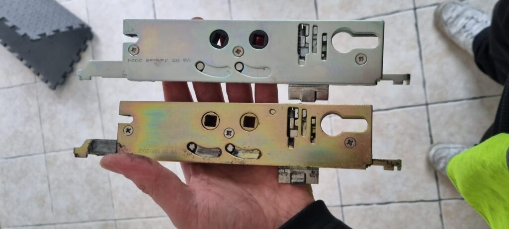 2 x Yale g2000 upvc door multi point locking gearboxes, one in silver and one in gold being held in hand