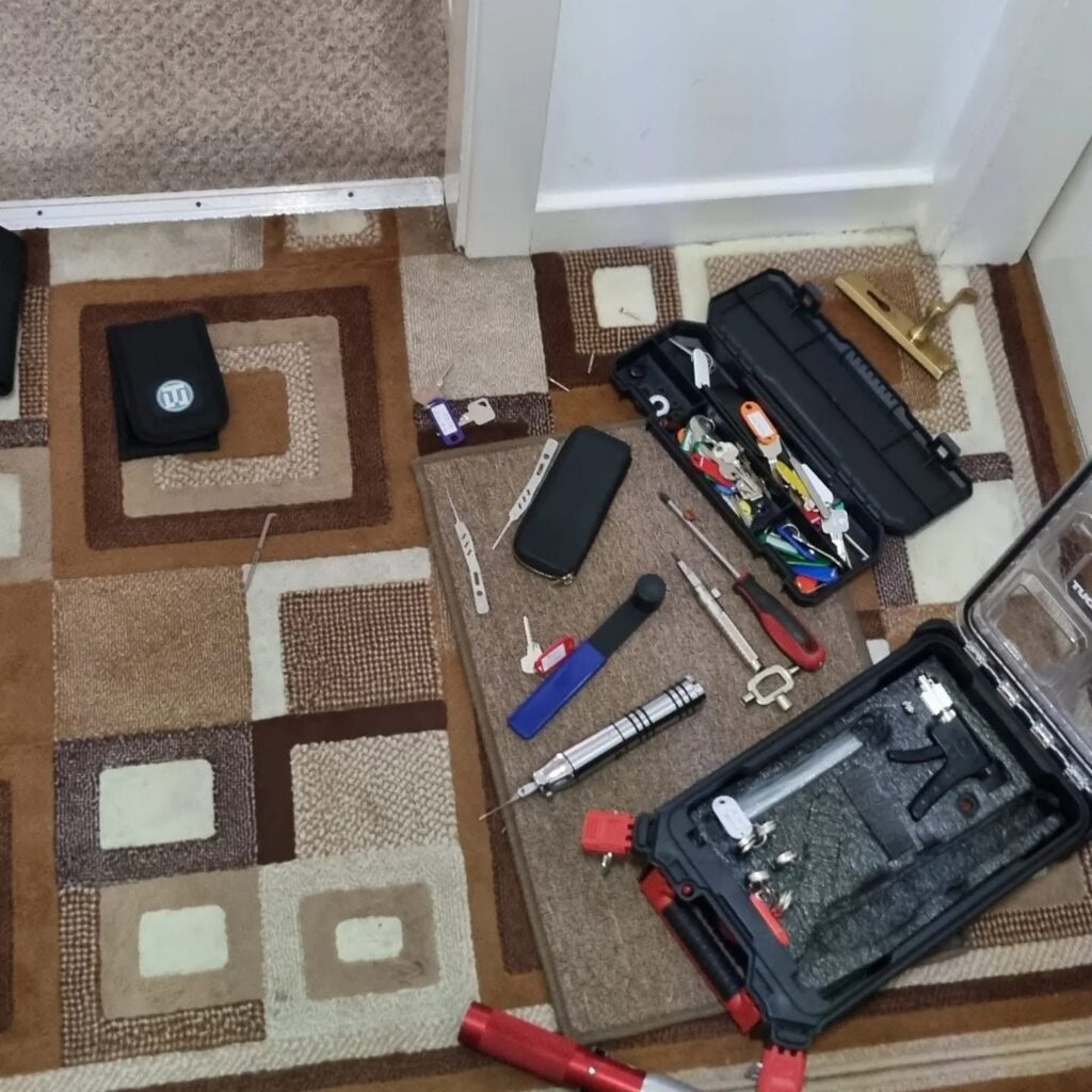 Lock picking equipment including manual picks, electric picking gun and bump keys laid on brown patterned carpet